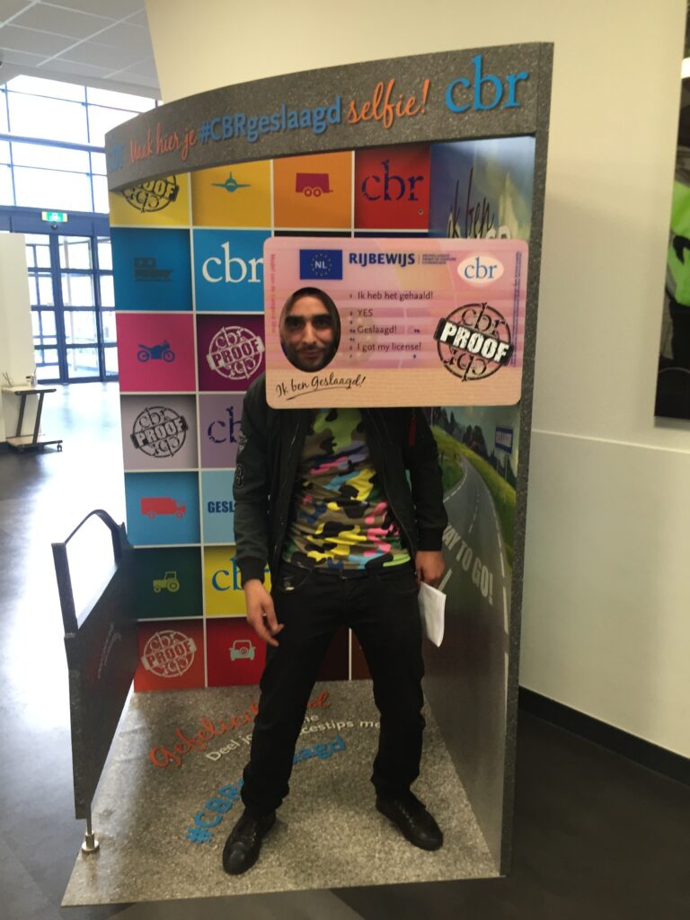 Geslaagde rijbewijsleerling poseert trots met hoofd in rijbewijsfoto.